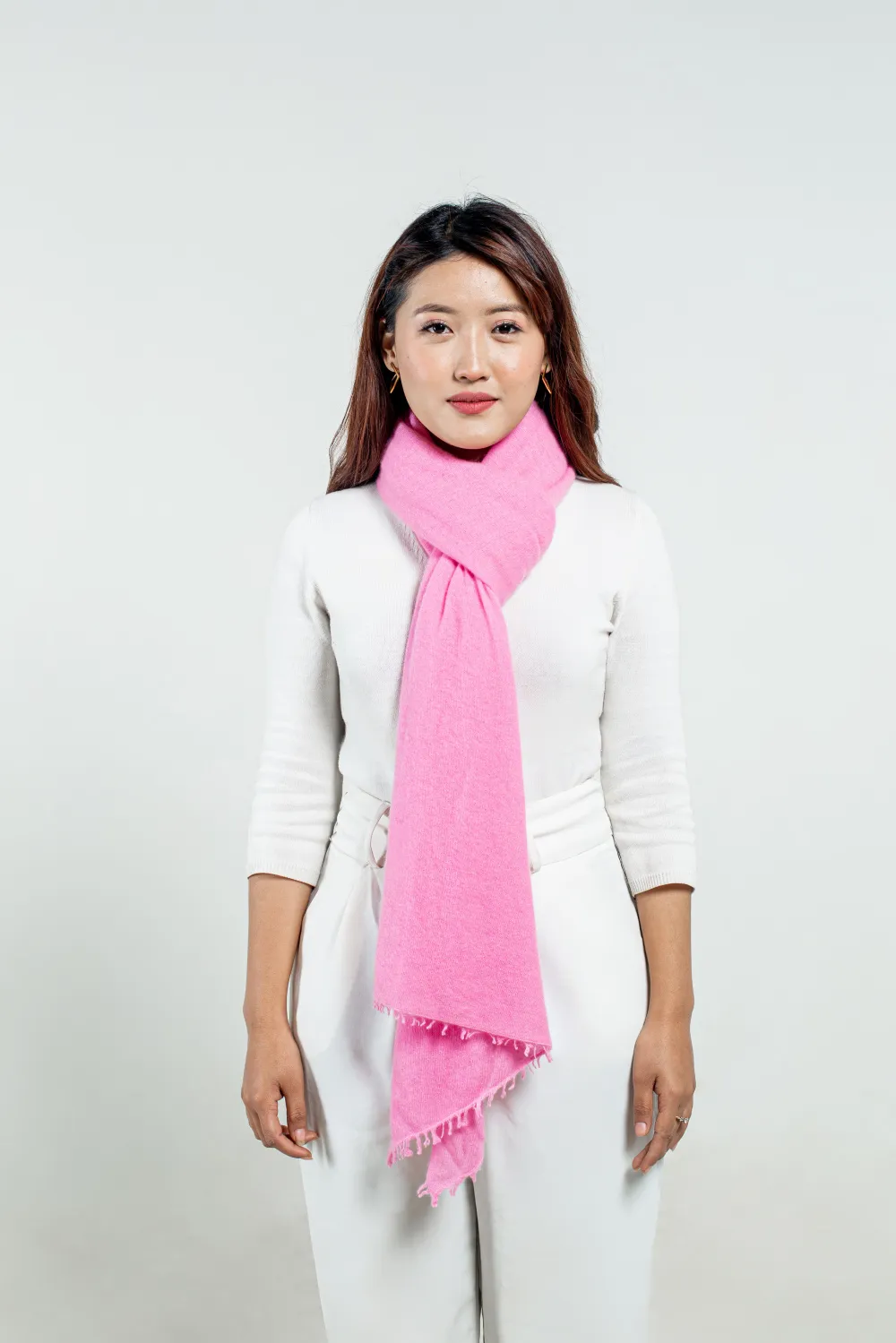 Woman styling a baby pink felted cashmere scarf.